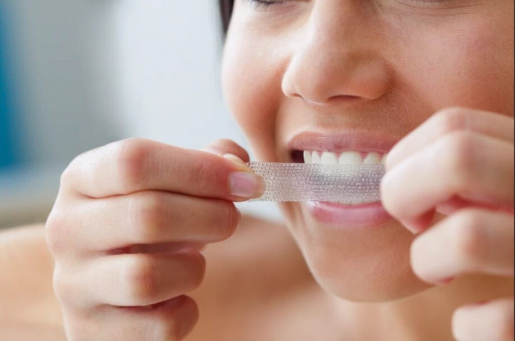 Kvinna applicerar tandblekningsremsa