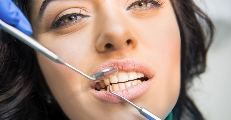 Tandläkarverktyg i munnen på kvinna